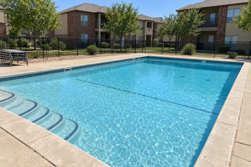 Apartment complex pool with a white finish inside a black metal fence