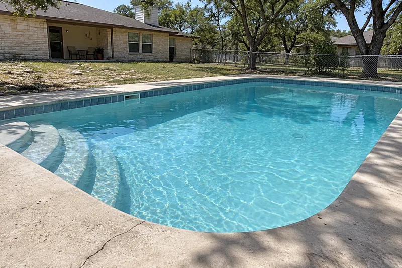 Backyard pool with a new light gray finish and soft blue water