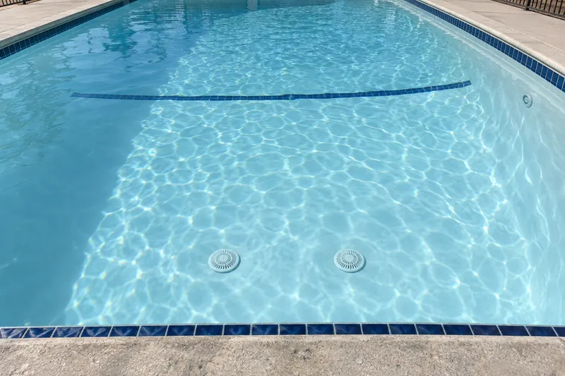 Clear water showing the main drain covers at a community pool's deep end
