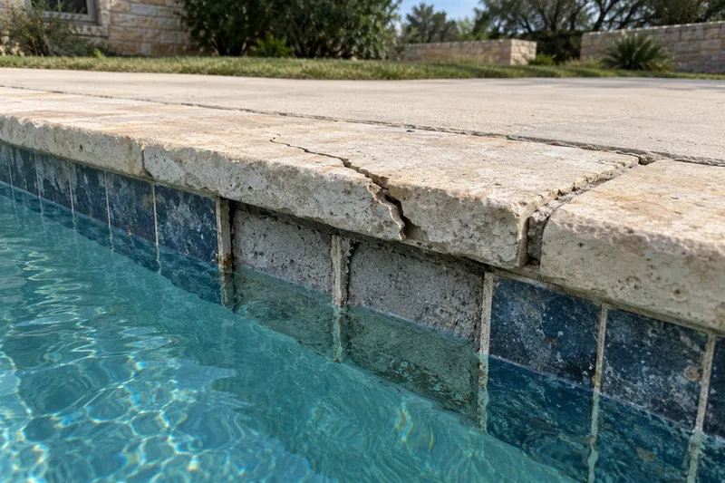 Cracked, lifted coping stone and an open joint at the pool deck