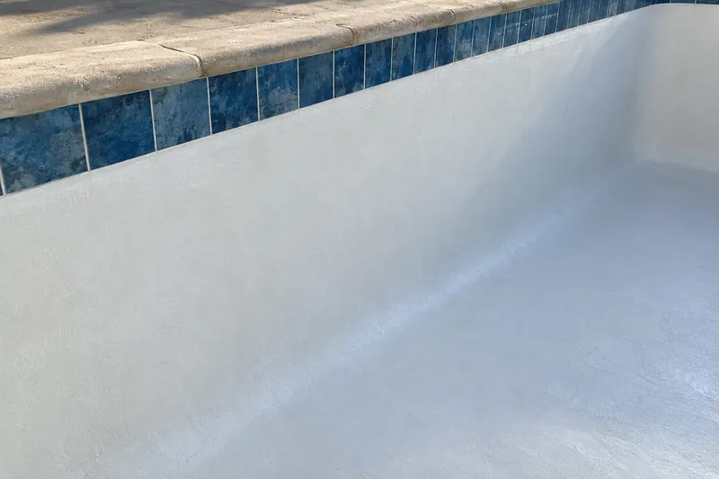 Freshly troweled white plaster meeting the waterline tile