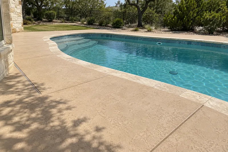 Light tan knockdown-textured pool deck around a backyard pool