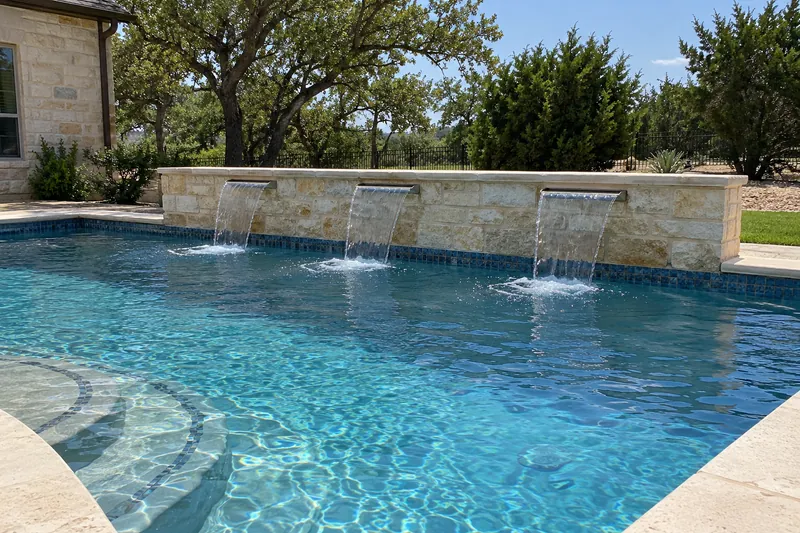 Three sheer-descent waterfalls pouring from a raised wall into a pool