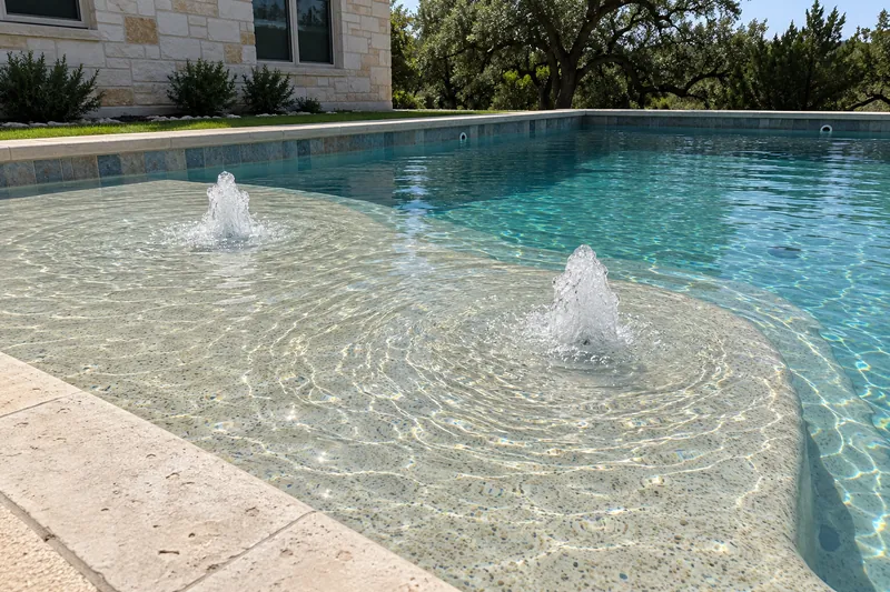 Wide sun shelf with two bubblers in a backyard pool