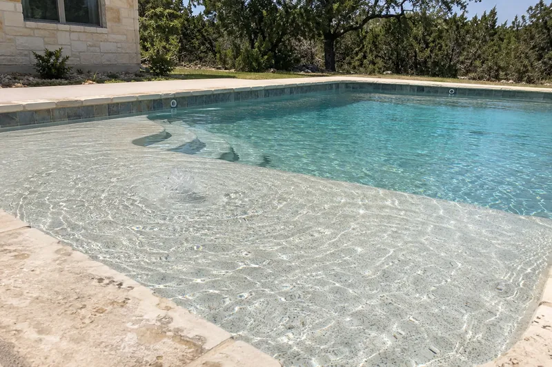 Shallow tanning ledge with a bubbler in a backyard pool