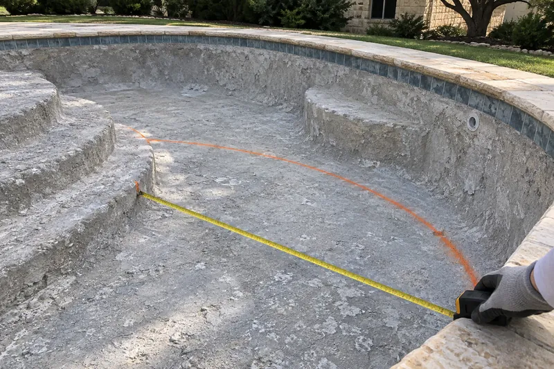Marking-paint outline of a new tanning ledge on a drained pool floor